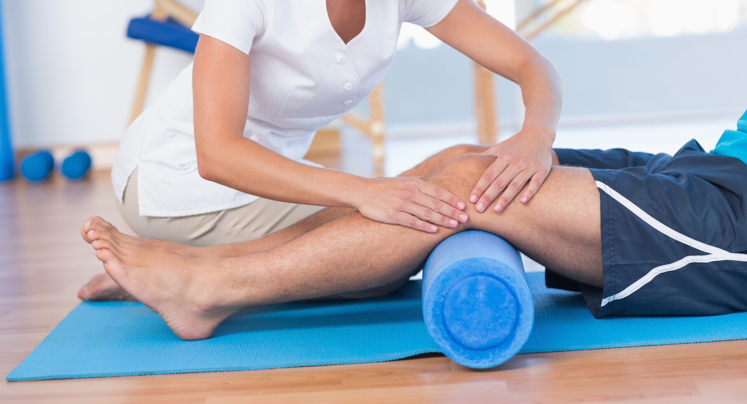 Trainer working with man on exercise mat in fitness studio